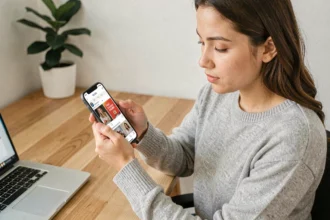 Jeune femme consultant des publicités sponsorisées sur les réseaux sociaux depuis son smartphone au bureau